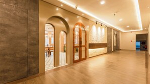 Un pasillo amplio con suelo de madera, arcos y luces empotradas.