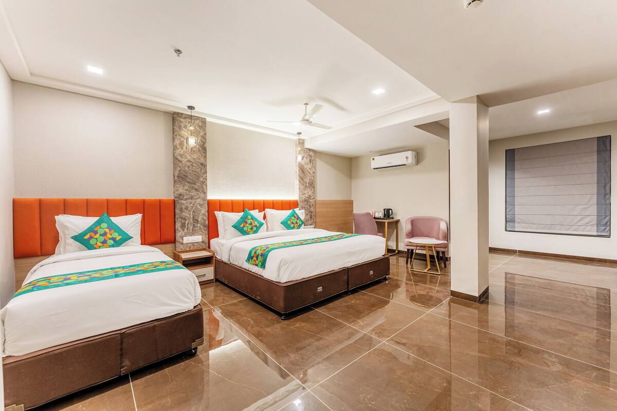 A hotel room with two beds, a sitting area, and a large window.