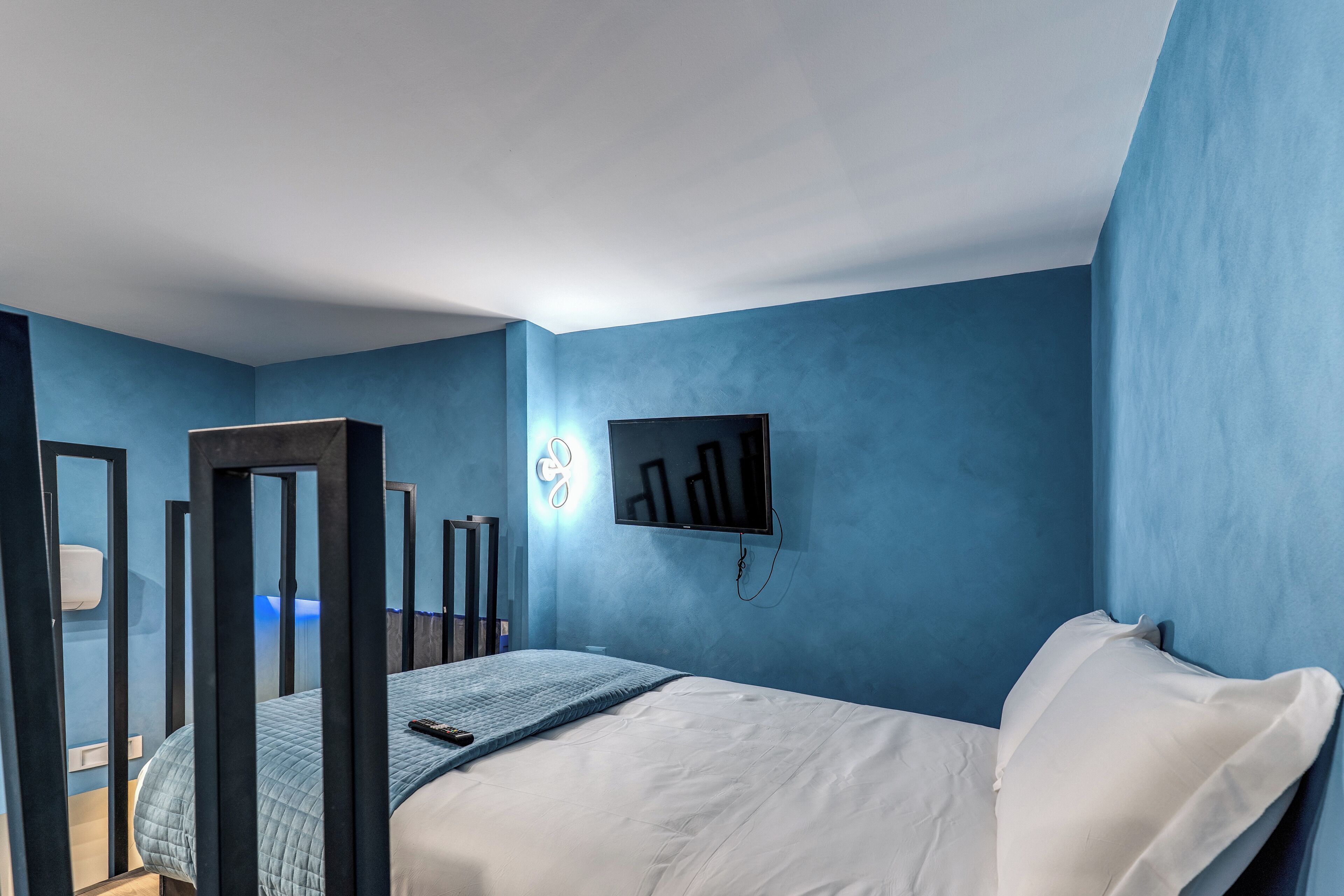 A bedroom with a bed, a TV mounted on the wall, and a mirror.
