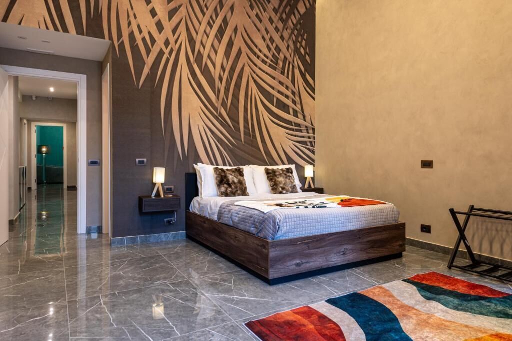 A modern bedroom with a large bed, a decorative wall, and a marble floor.