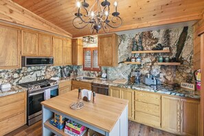 A kitchen with wooden cabinets, a granite countertop, a stove, and a chandelier. - Two Bedrooms w/En-Suite Bathrooms!PET FRIENDLY 🐾! HOT TUB! Fire Pit! Close to Bear Mountain! (Big Bear Lake)