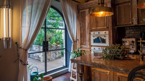 A kitchen with wooden cabinets, a large window with curtains, a stove, and a sink. - Jingdezhen Homestay Outside the Window (Jingdezhen)