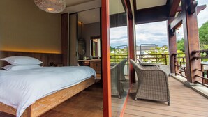 A bedroom with a wooden bed, a wicker chair, and a balcony with a view of greenery. - Jingdezhen Homestay Outside the Window (Jingdezhen)
