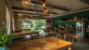 A restaurant with wooden tables and chairs, hanging woven light fixtures, and a green wall with shelves. - Jingdezhen Homestay Outside the Window (Jingdezhen)