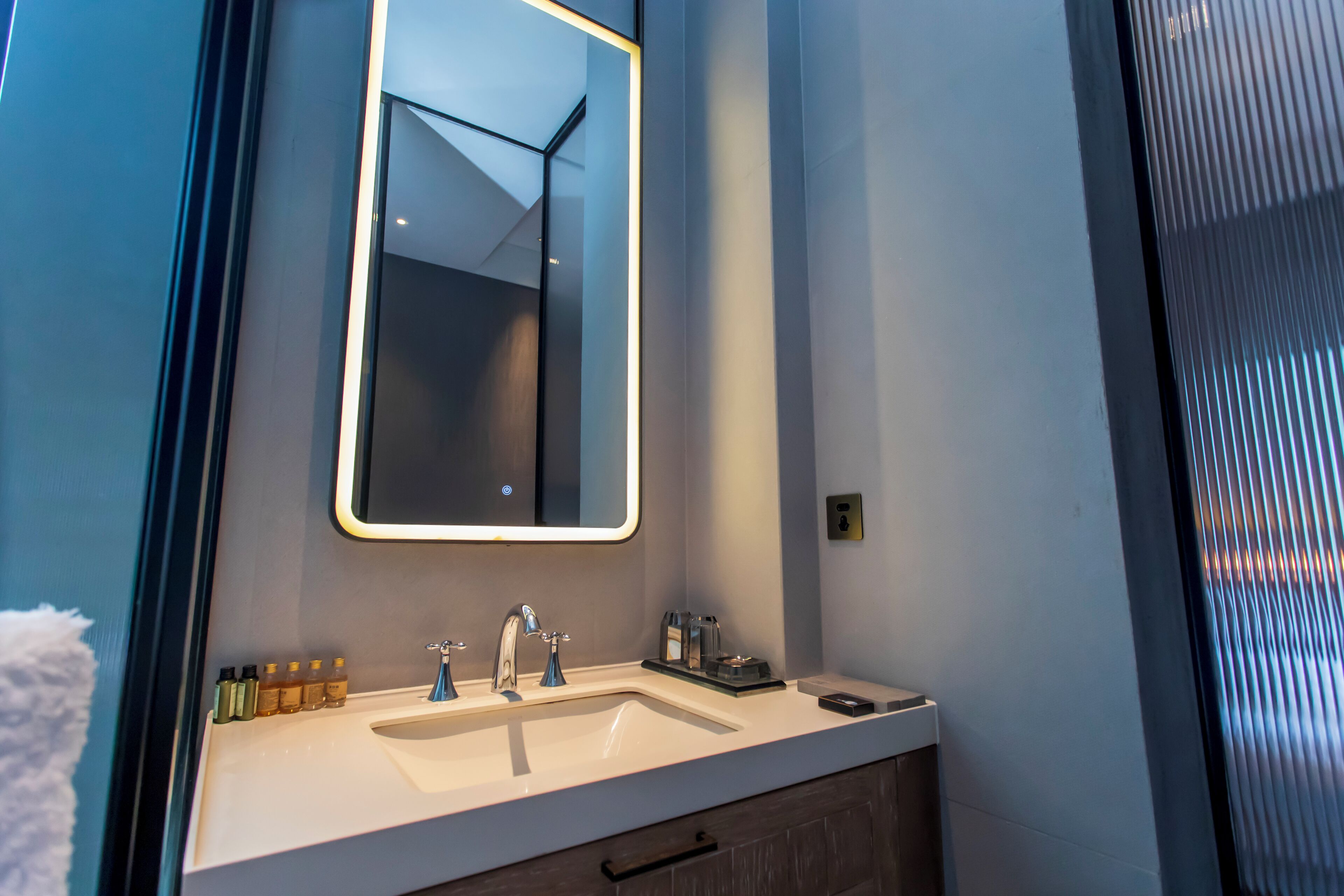 A modern bathroom with a white sink, two faucets, a mirror, and a towel rack.