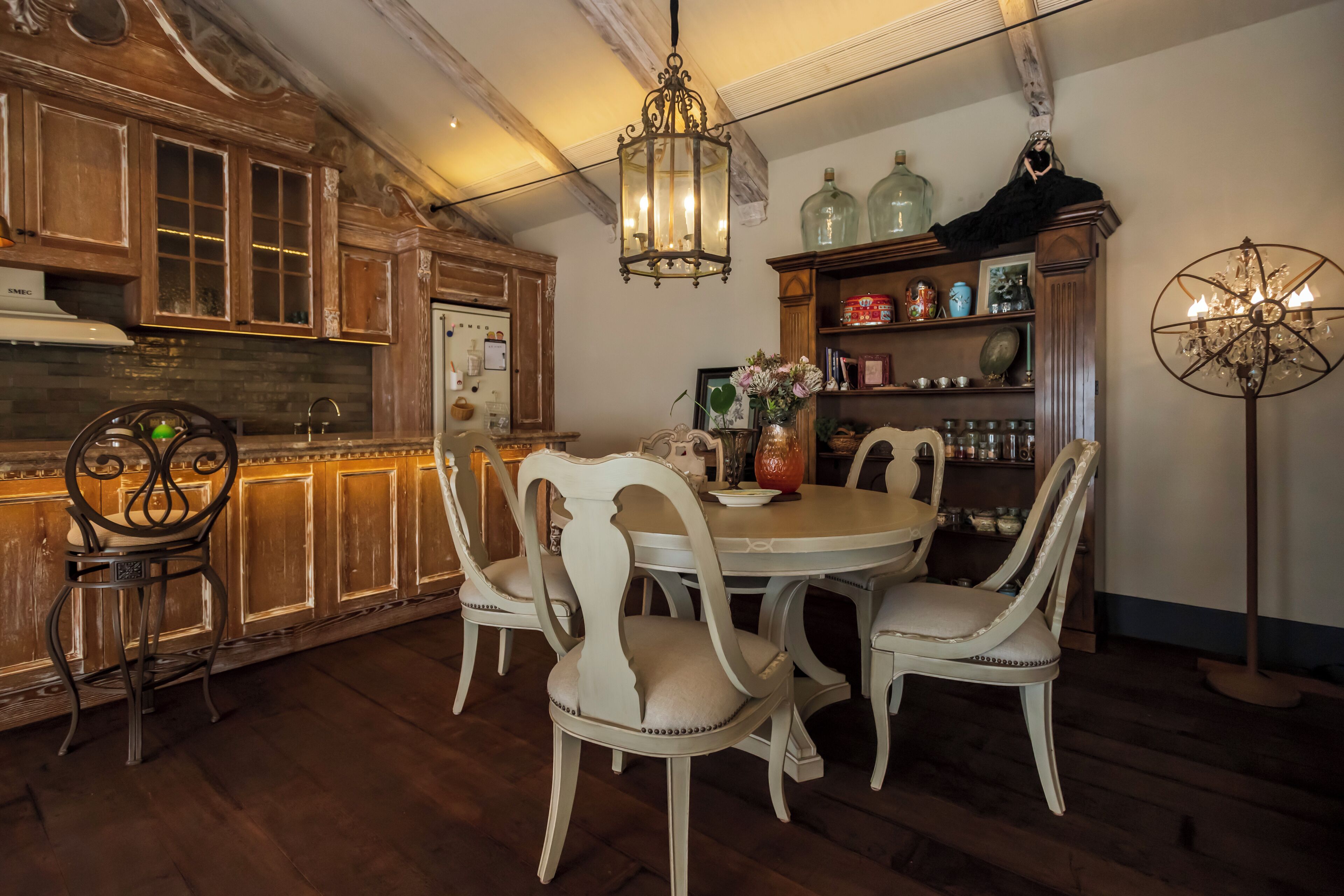 A traditional kitchen with wooden cabinetry, a dining table with chairs, and a chandelier.