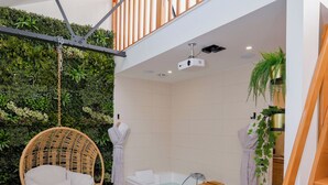 Um banheiro moderno com uma cadeira suspensa, uma banheira e uma mesa de massagem.