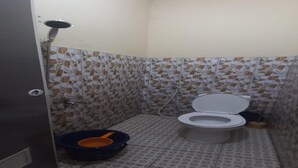 Une petite salle de bain avec des toilettes, une douche et une poubelle.