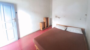 Une pièce avec un lit, une armoire en bois et une porte bleue.