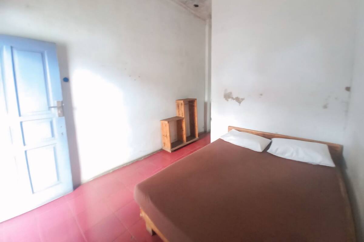 A room with a bed, a wooden cabinet, and a blue door.