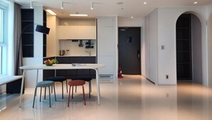 A modern kitchen with white cabinets, a dining table with two chairs, and a kitchen island with a fruit bowl. - Sota Suite Yangyang Granbay (Yangyang)