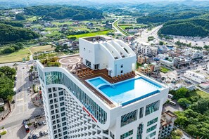 A high-rise hotel with a rooftop pool, surrounded by a cityscape and greenery. - Sota Suite Yangyang Granbay (Yangyang)