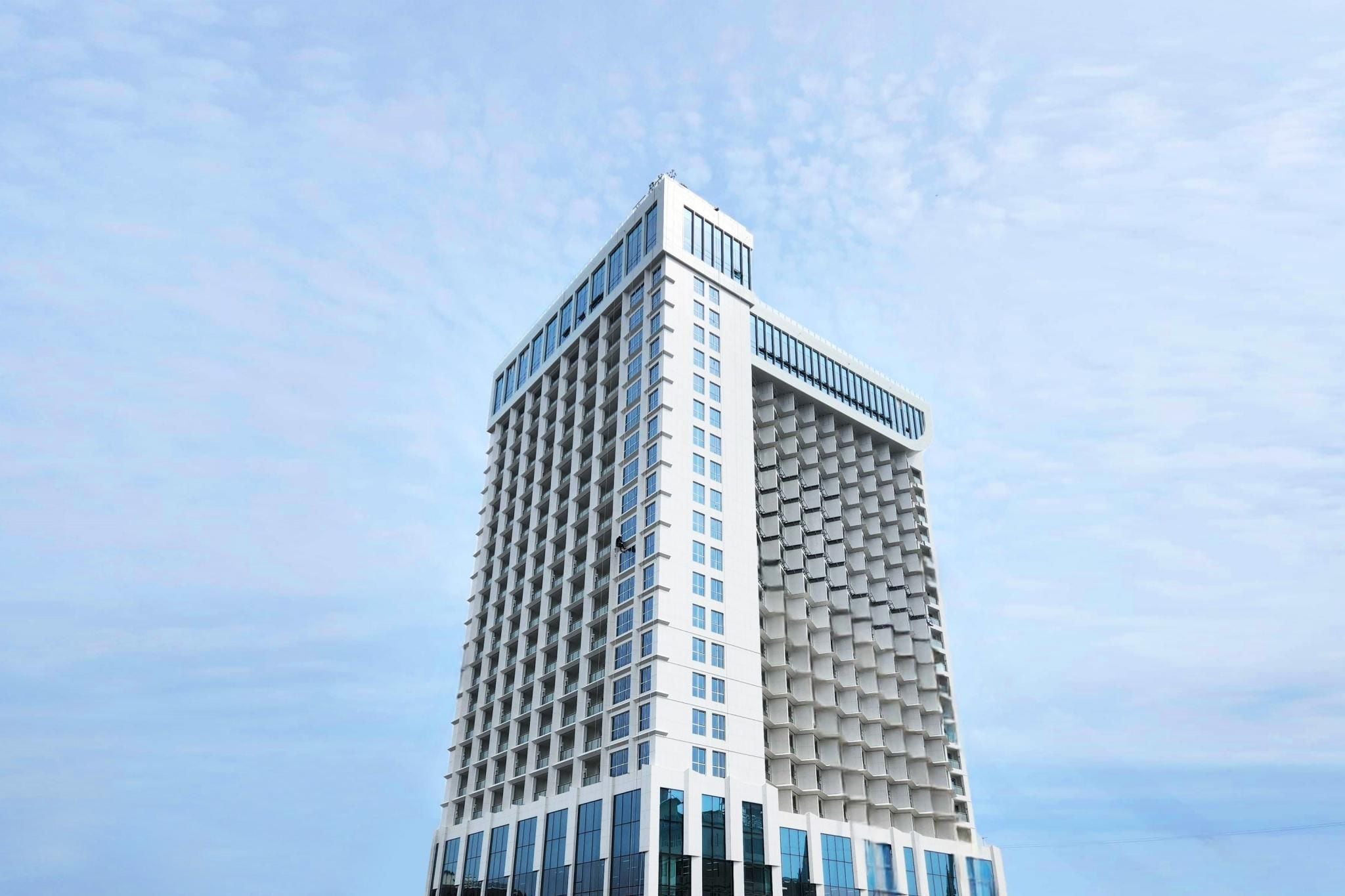 A modern high-rise building with a unique architectural design, featuring a grid-like facade and a flat roof.