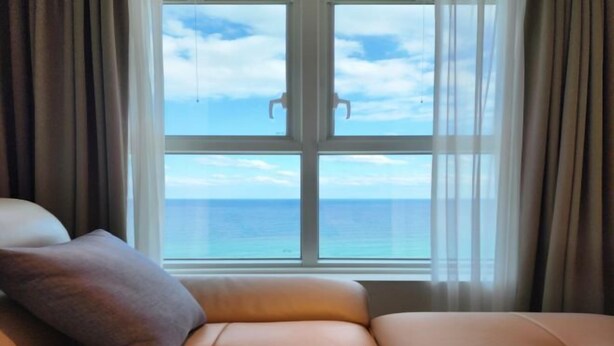 A room with a large window, a sofa, and a view of the ocean. - Sota Suite Yangyang Granbay (Yangyang)