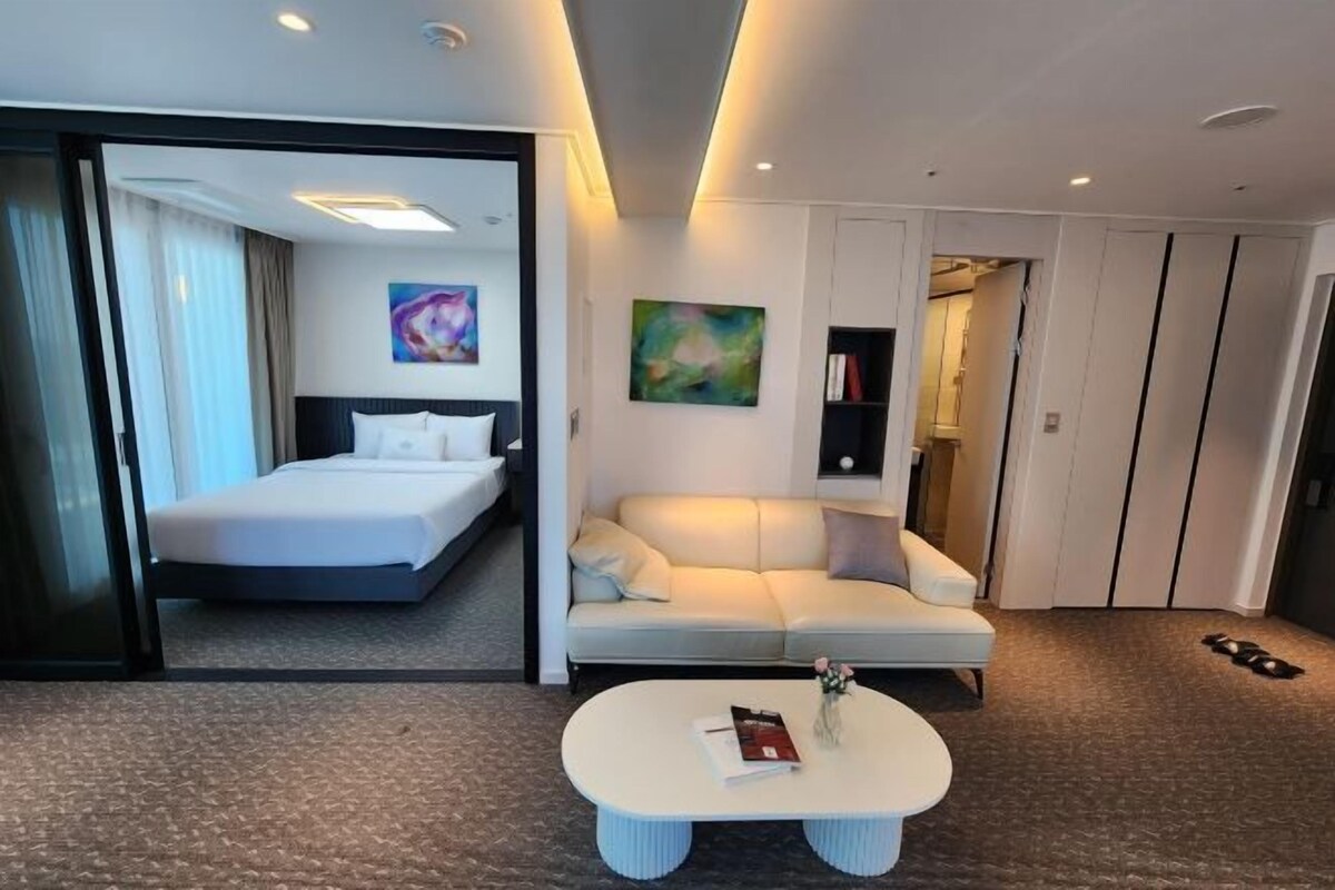 Een moderne hotelkamer met een bed, een bank, een salontafel en een schilderij aan de muur.