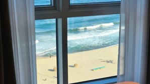 A window with a view of a beach, ocean waves, and a sandy shore. - Sota Suite Yangyang Granbay (Yangyang)