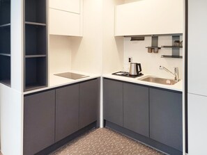 A compact kitchen with a built-in sink, a kettle, and a tablet on the counter. - Sota Suite Yangyang Granbay (Yangyang)