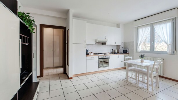Une cuisine moderne avec des meubles blancs, une table à manger et un four à micro-ondes.