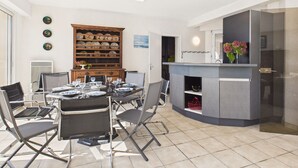 Uma sala de jantar com mesa redonda, cadeiras, buffet e cozinha equipada com forno embutido e pia.