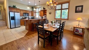 Una cocina con armarios de madera, un refrigerador, un microondas y una mesa de comedor para seis personas.