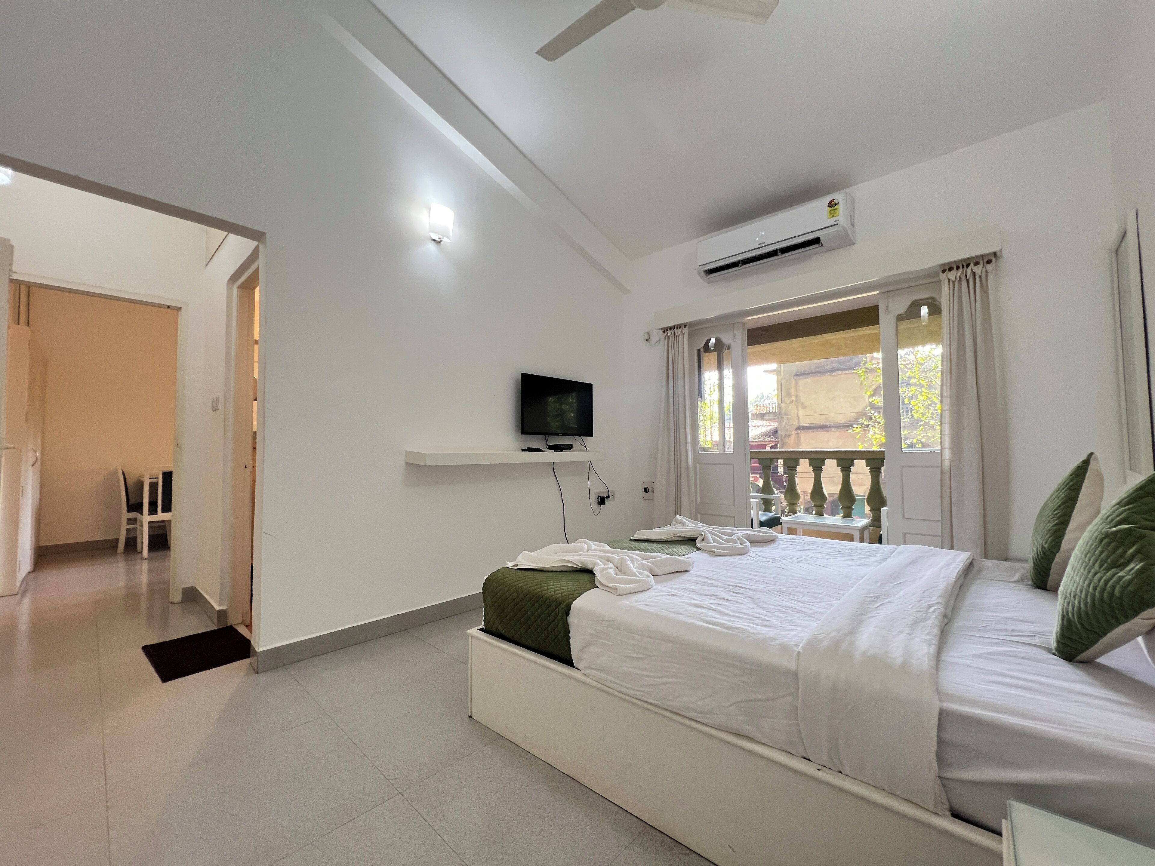 Un dormitorio con una cama, un televisor en un estante, aire acondicionado y vistas al exterior.