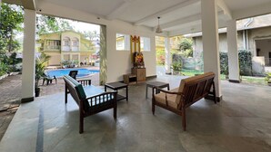 A spacious indoor area with a pool, outdoor seating, and a view of a building with multiple floors. - Gaur Opulent Goa (Candolim)