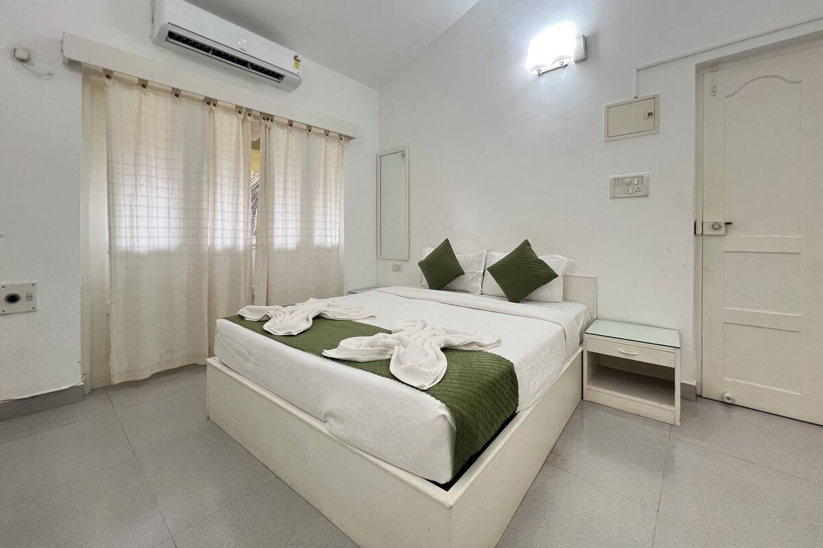 A bedroom with a bed, nightstand, and a door.