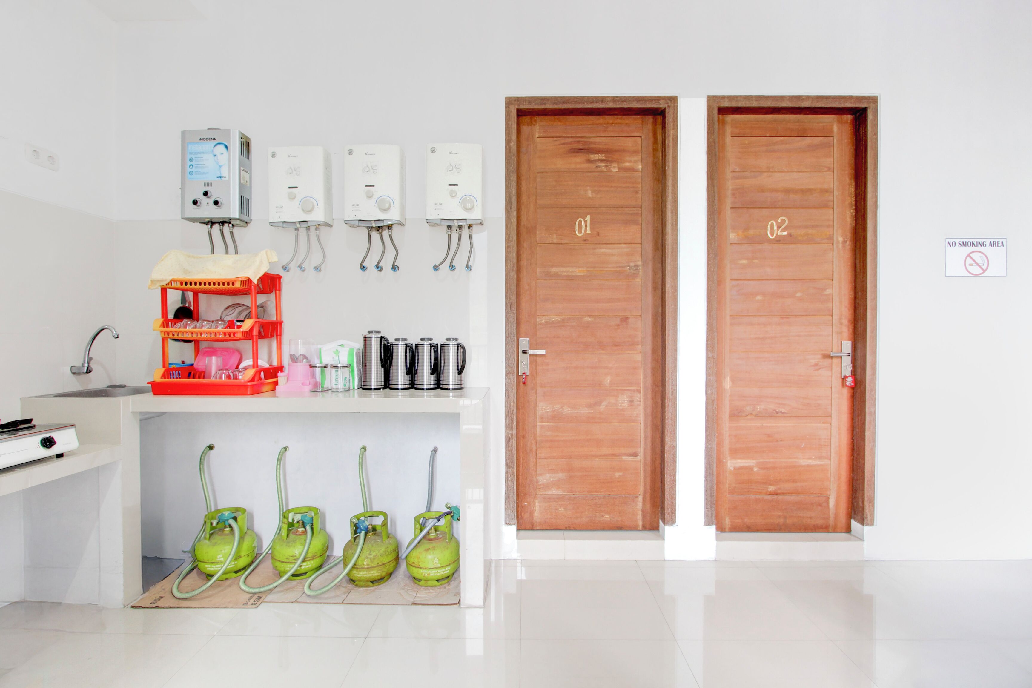A clean, modern kitchen with two wooden doors, a coffee machine, and gas cylinders.