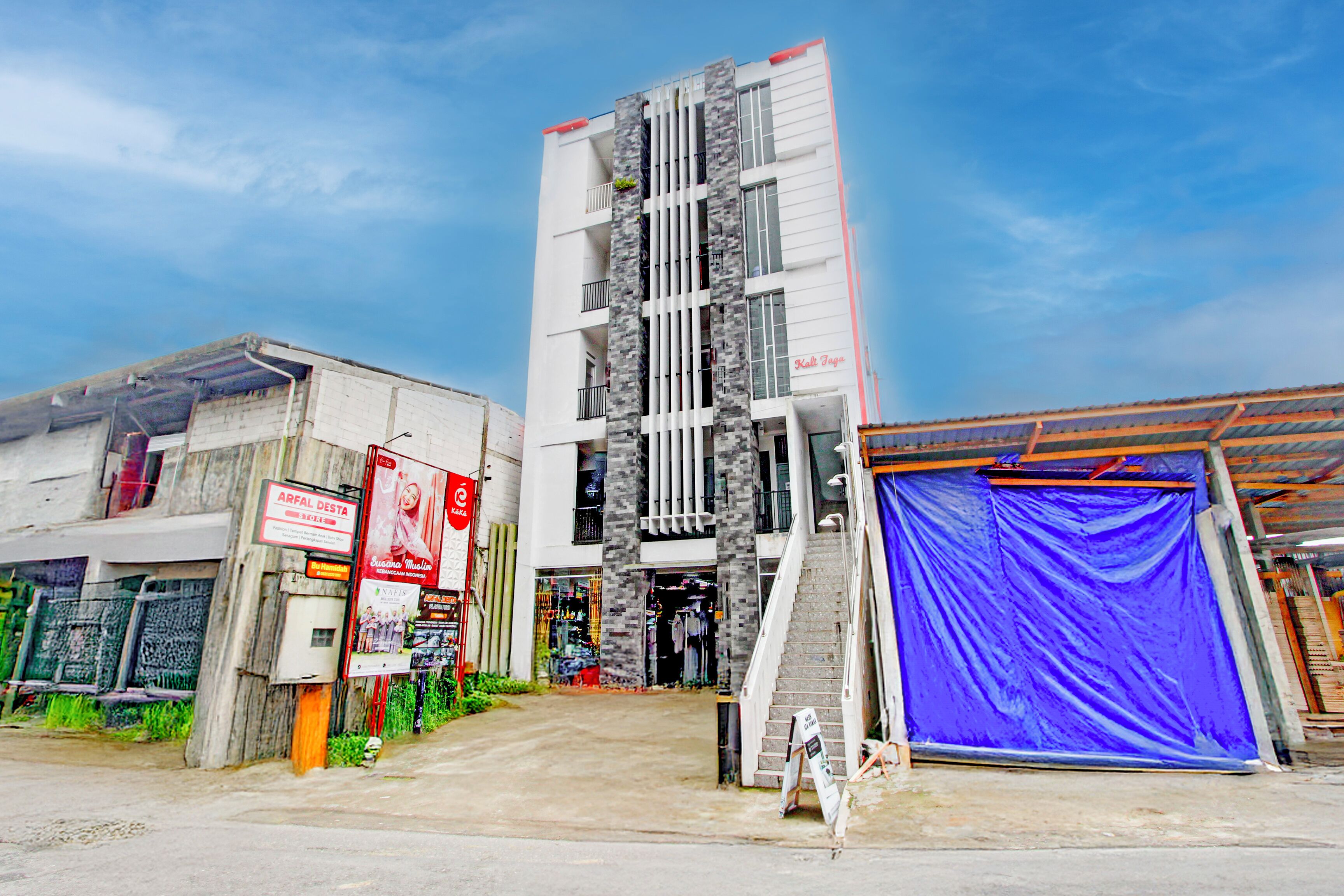 A multi-story building with a modern facade, a staircase leading to the entrance, and a blue awning.