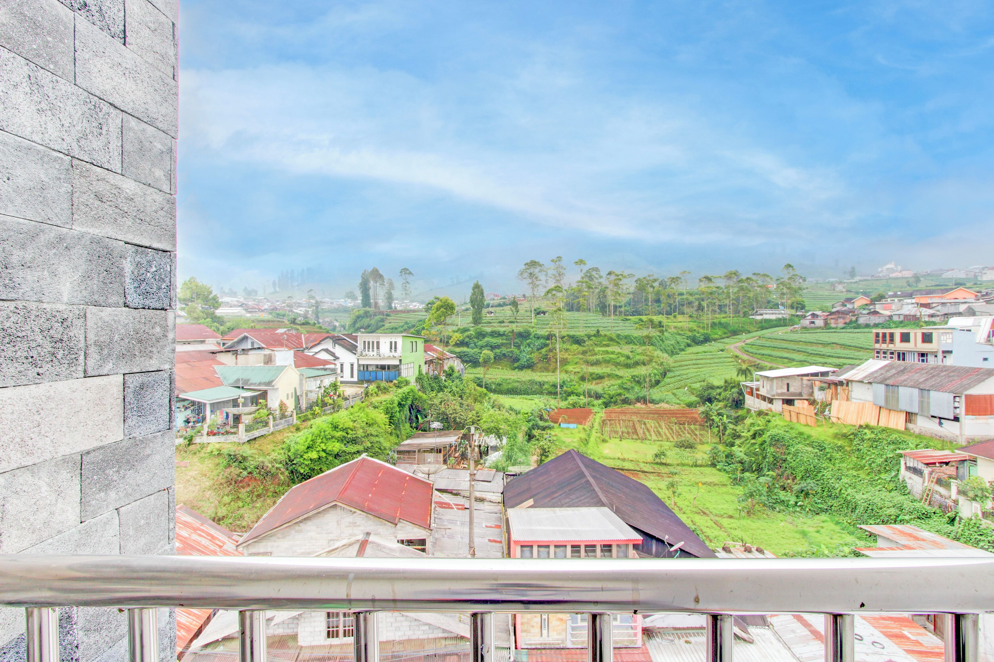 A residential area with houses, green fields, and a clear sky.