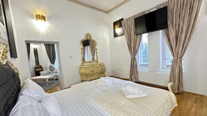 A hotel room with a large bed, a dresser, a mirror, and a TV. - 1 Bed Royal Escape - City Central, Wifi (Arad)