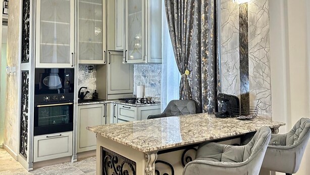 A modern kitchen with white cabinets, a granite countertop, and a built-in stove. - 1 Bed Royal Escape - City Central, Wifi (Arad)