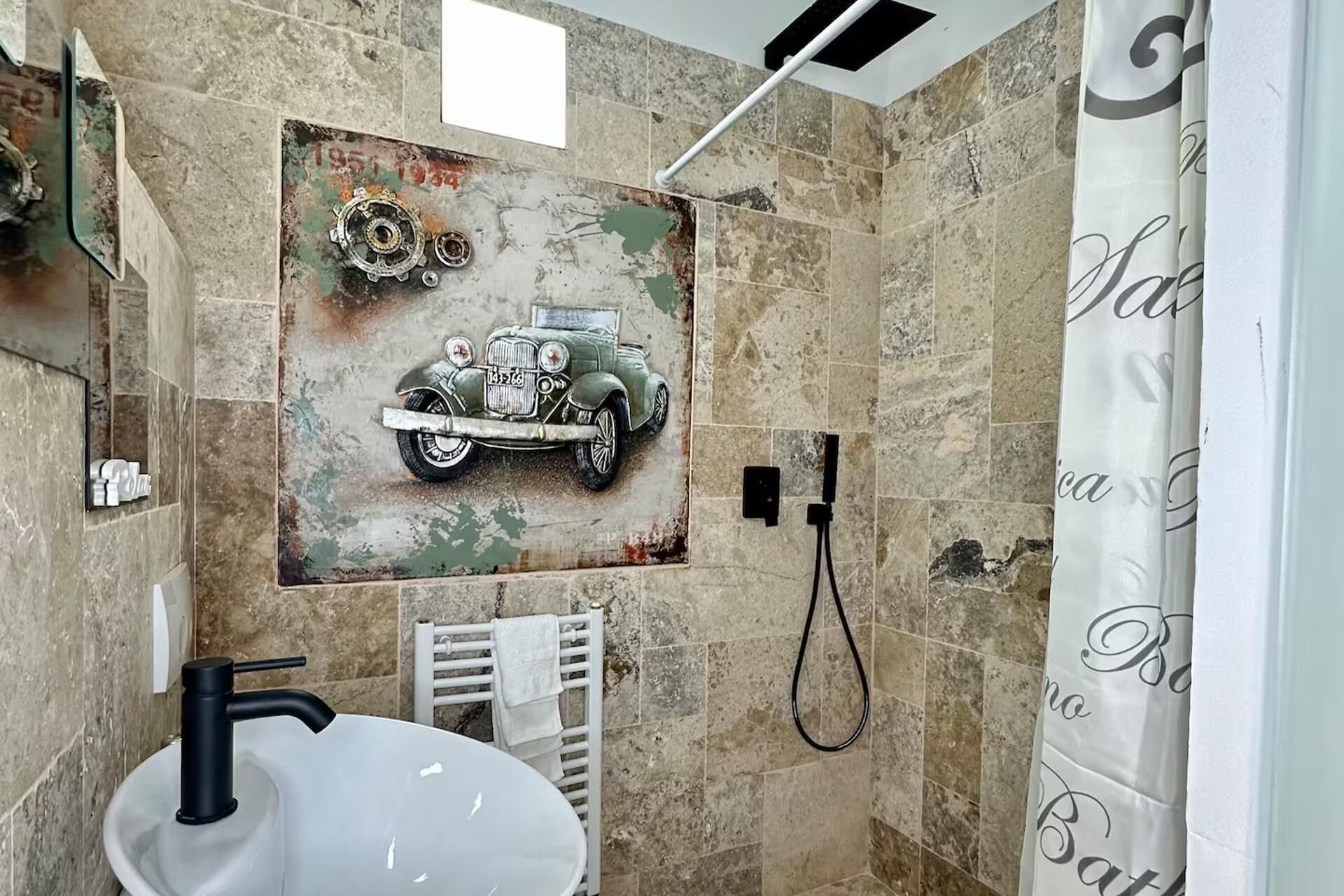 A bathroom with a vintage car mural, a white sink, and a shower.