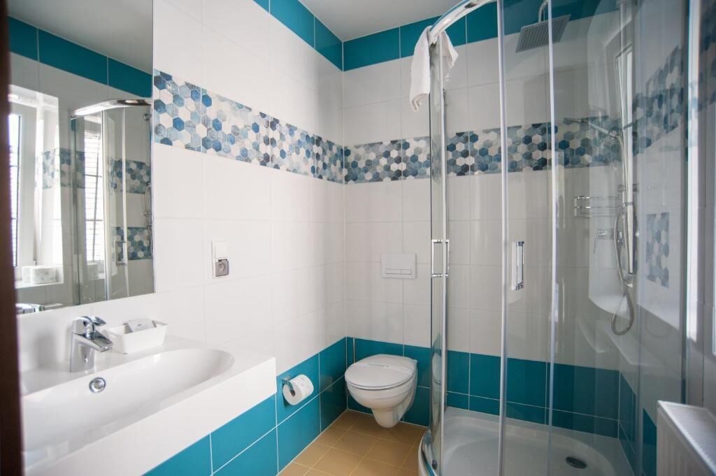 A modern bathroom with a bathtub, toilet, and glass-enclosed shower.