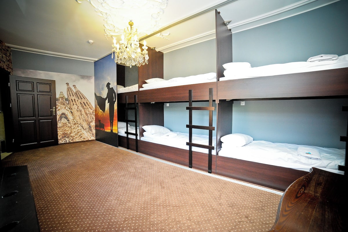 A room with bunk beds, a chandelier, and a mural on the wall.
