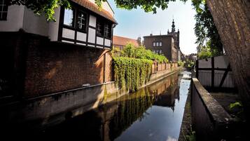 A narrow canal with a building on one side and a tree on the other.