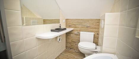 A compact bathroom with a white sink, a toilet, and a bathtub.