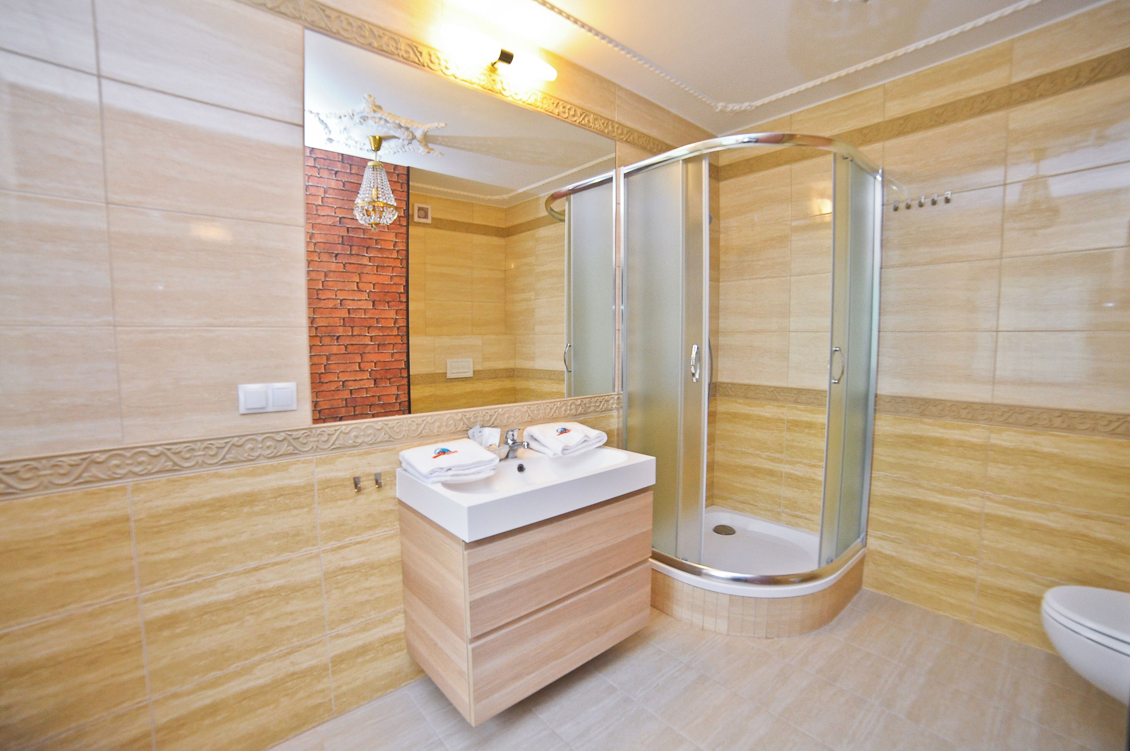 A modern bathroom with a glass-enclosed shower, a wooden vanity with a white countertop, and a large mirror above the sink.