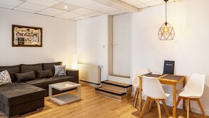 A modern living room with a sofa, coffee table, and a dining area with chairs and a table.