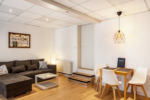 A modern living room with a sofa, coffee table, and a dining area with chairs and a table. - Apartment 'Ferien- Und Handwerkerwohnung' with Wi-Fi (Römhild)