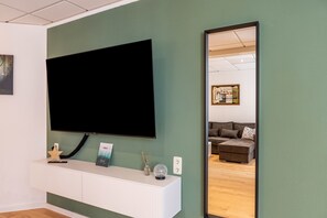 A room with a mounted TV, a white console table with a star decoration, a framed picture, and a globe. - Apartment 'Ferien- Und Handwerkerwohnung' with Wi-Fi (Römhild)
