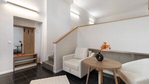 Een moderne woonkamer met een bank, een ronde houten tafel en een trap.