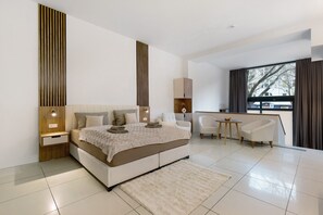 A modern bedroom with a large bed, bedside tables, a desk, and a chair.