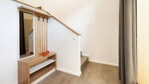 Eine Treppe mit Holzwand, eine Bank, ein Spiegel und ein Heizkörper im Hintergrund.
