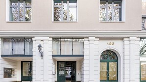 Ein Gebäude mit großem Bogenportal, einem Schild mit der Nummer 103 und einer Straßenlaterne.