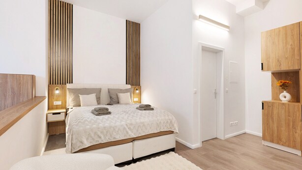 Ein modernes Schlafzimmer mit einem großen Bett, Nachttischen, einem Kleiderschrank und einer Tür.