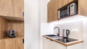 A compact kitchen with a microwave, kettle, and coffee maker on a countertop. - City Loft Kurfürstendamm | Walk to Everything (3) (Berlin)