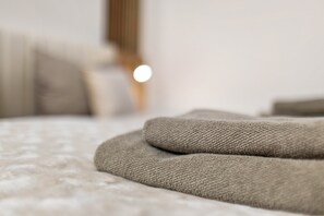 A close-up of a textured fabric, possibly a blanket or throw, on a bed with a blurred background. - Smart Home Studio | Ku’damm Living (5) (Berlin)
