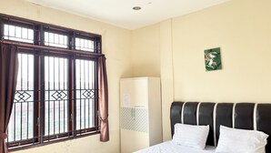 Una habitación de hotel con cama, armario, ventana con cortinas e imagen colgada en la pared.
