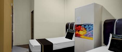 A hotel room with two beds, a wardrobe, and a painting on the wall.
